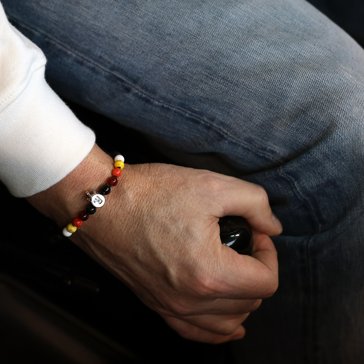 Man wearing beaded bracelet while driving, motorsport inspired jewellery for men